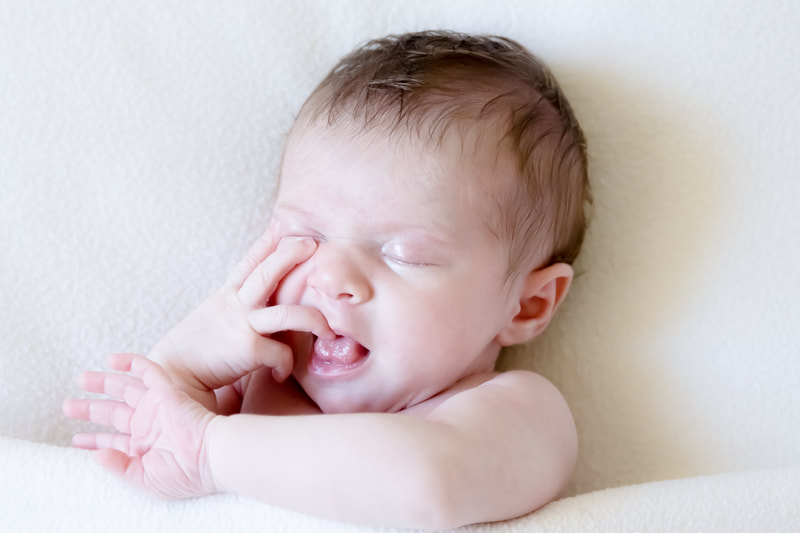 Newborn baby with hand in mouth