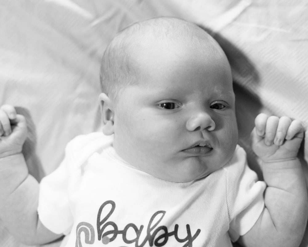 Newborn baby laying on bed, black and white, lifestyle newborn photography
