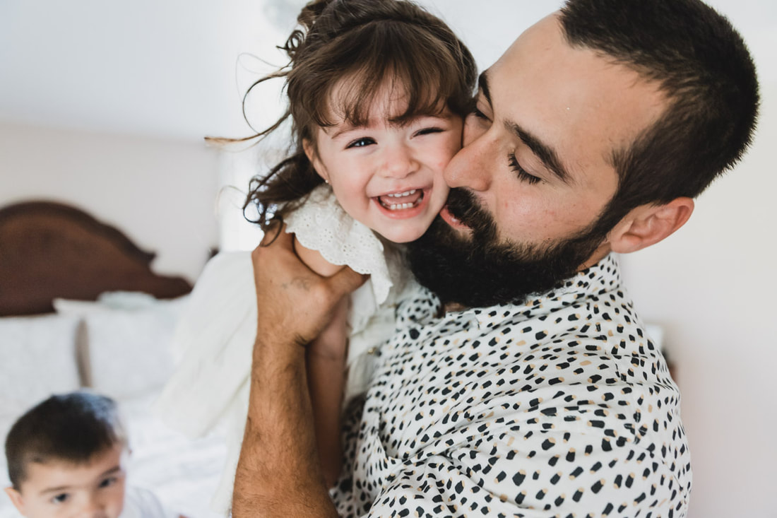 Dad holding toddler girl in arms laughing, in-home lifestyle newborn photography