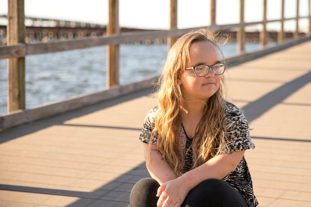 13 year old girl sitting on pier looking to the side, Bradenton Riverwalk, Florida