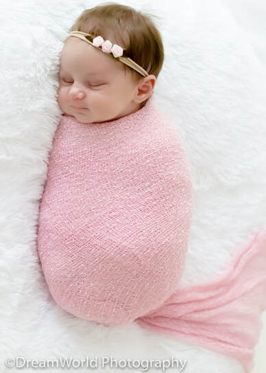 Posed sleeping baby in pink wrap