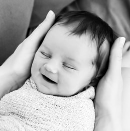 Black and white smiling baby laying on mom's lap