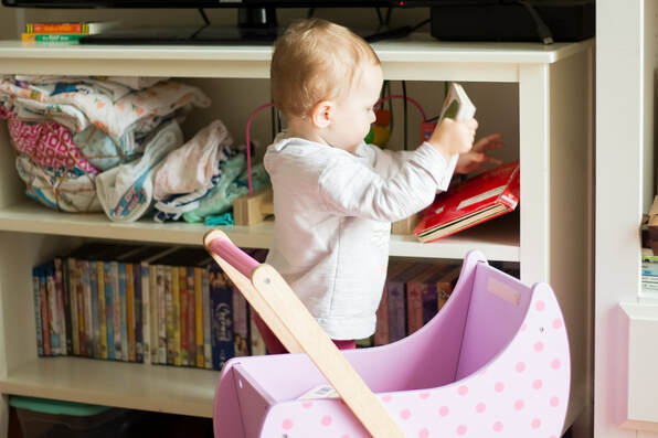 Toddler girl picking up book from bookshelf