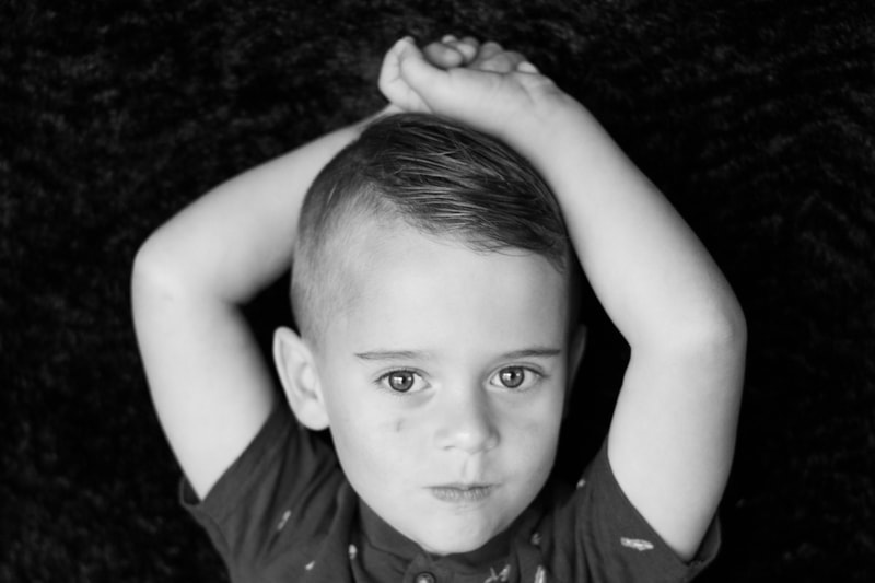 Black and white little boy with arms up over head, school photography