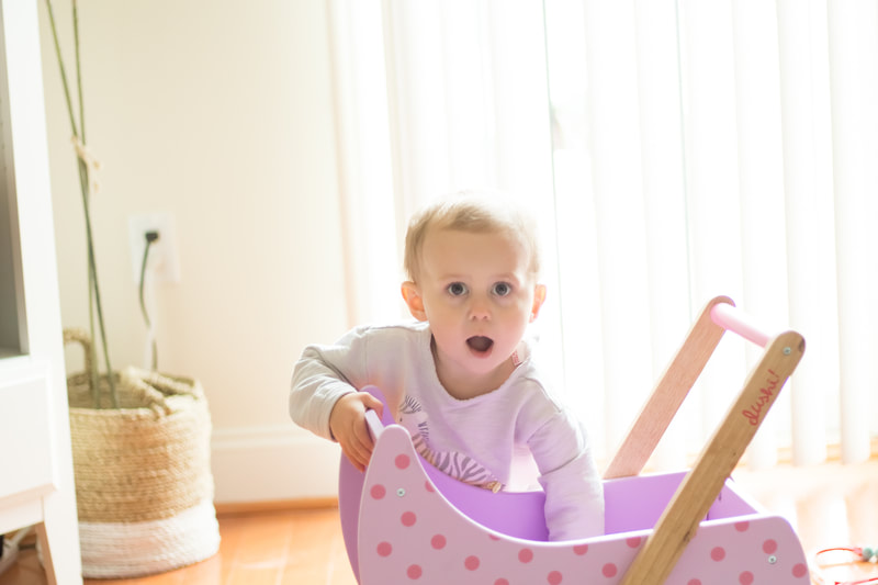 One year old girl playing with cart
