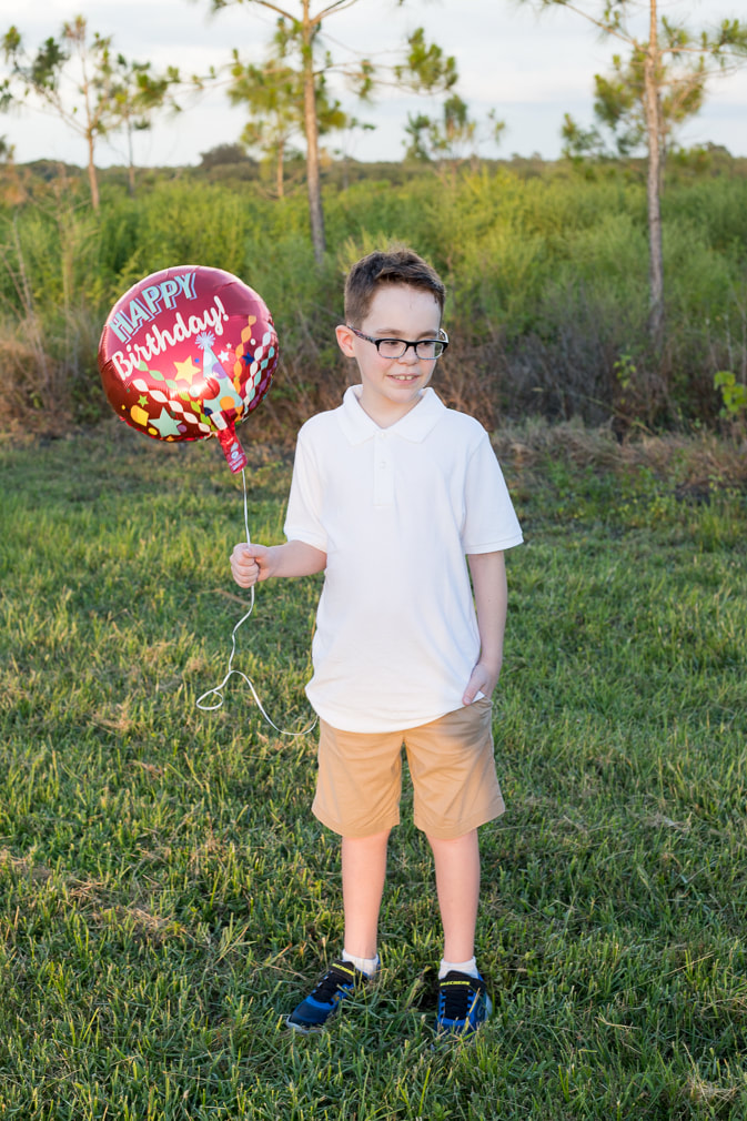 9 year old boy standing outside holding birthday balloon, Celery Fields Sarasota