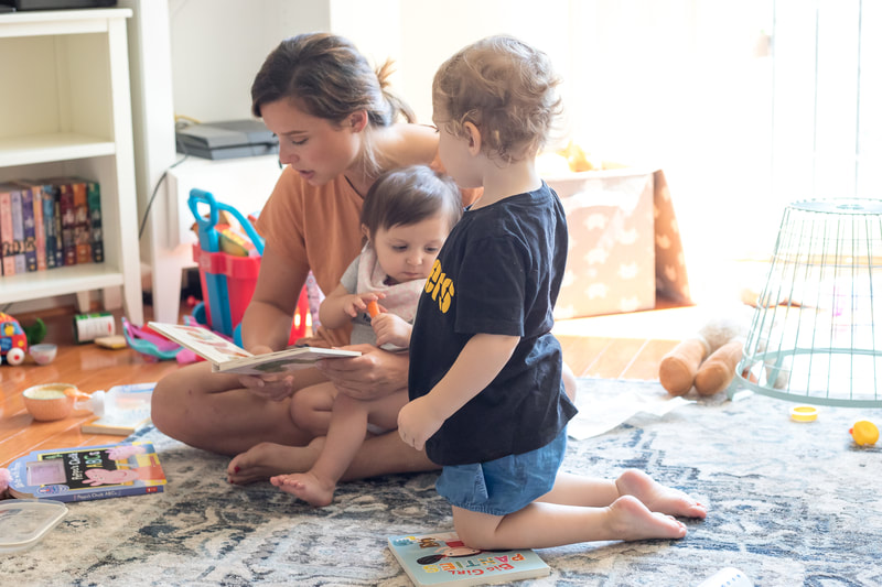 Mother reading to children on floor in home.