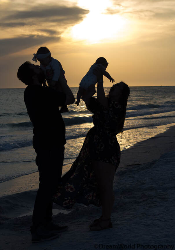 Sunset silhouette, couple holding up children, Siesta Key Beach, Florida